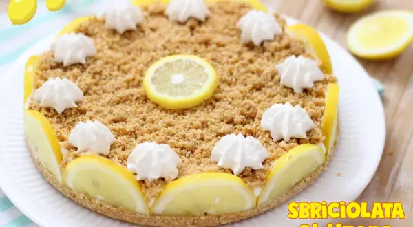 Deliziosa sbriciolata al limone senza cottura, decorata con fettine di limone e ciuffetti di panna. Perfetta per un dessert fresco e goloso.