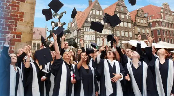 Absolventen der Apollon Hochschule werfen ihre Hüte in die Luft. Tolle Erfahrungen und ein erfolgreicher Abschluss!