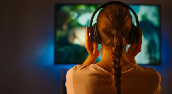 Dziewczyna w słuchawkach zanurzona w świecie filmu, gdzie muzyka buduje nastrój.