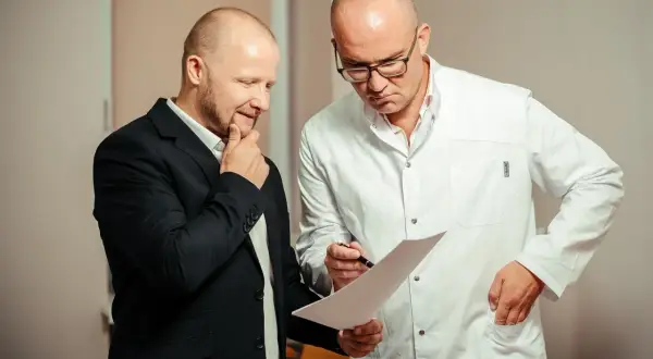 Lekarz w białym kitlu omawia z pacjentem wyniki badań, analizując rokowania dotyczące raka cewki moczowej.