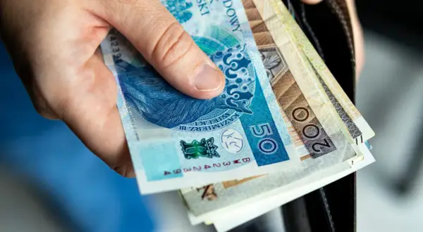 Dłoń trzyma polskie banknoty. Wkrótce jawność wynagrodzeń 2026, więc warto wiedzieć, ile zarabiamy.
