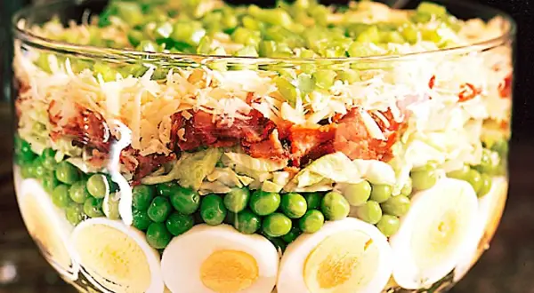 Lager på lager i en glasskål: ägg, gröna ärtor, sallad, bacon, ost och paprika. Ett härligt sallad recept!