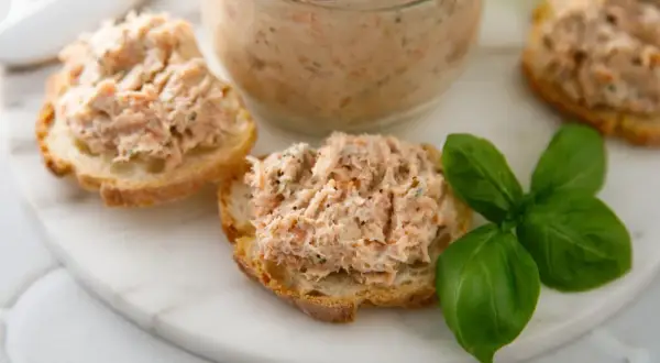Pyszna pasta rybna na chrupiących grzankach, ozdobiona świeżą bazylią. Idealna na szybką przekąskę.