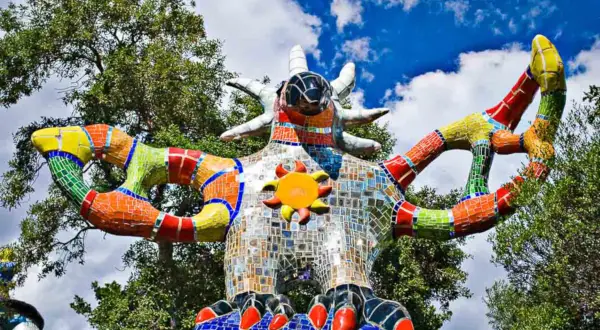 La scultura colorata del Giardino dei Tarocchi in Toscana, con il suo sole radioso e le braccia aperte, sembra accogliere i visitatori in un mondo magico.