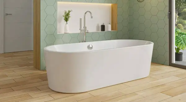 Une élégante baignoire îlot blanche trône sur un parquet en bois clair, sous un mur aux carreaux hexagonaux vert menthe.