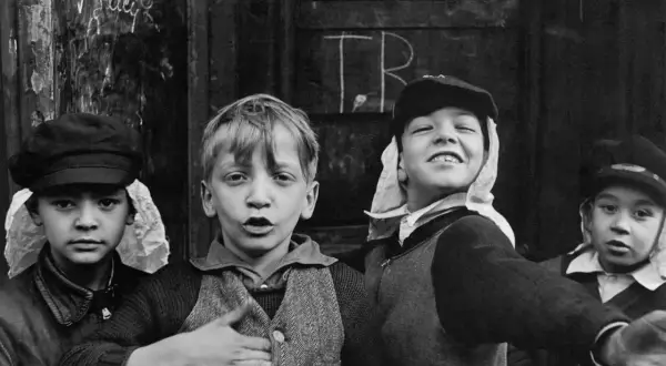 Bambini con cappelli, un'immagine che ricorda i grandi fotografi famosi, con un'espressione vivace e un gesto di invito.