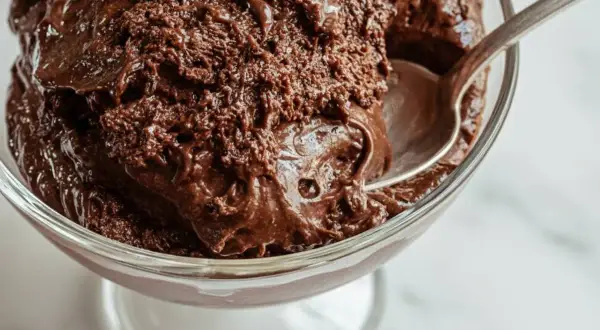 En sked tar en tugga av krämig chokladmousse i en glasskål. Perfekt för ett enkelt chokladmousse recept.