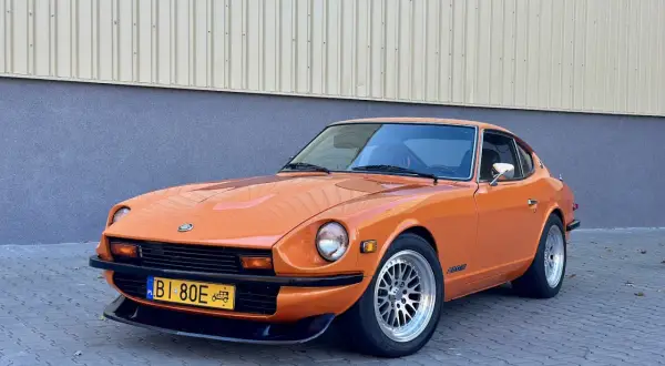 Pomarańczowy Datsun 280Z z lat 70. na tle budynku. Klasyk motoryzacji gotowy na przejażdżkę.