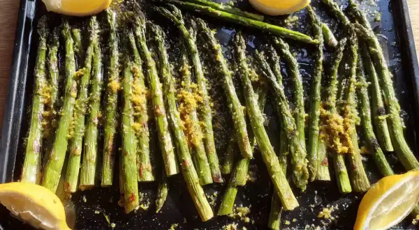Ugnsbakad sparris med citron och kryddor på en plåt. Perfekt som tillbehör till middagen.