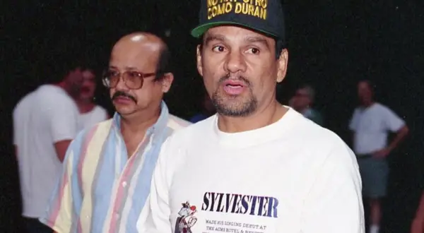 Roberto Duran reach, wearing a cap that says "No Hay Otro Como Duran." He's in a white t-shirt with "Sylvester" printed on it.