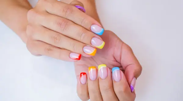 Kolorowe paznokcie na lato: francuski manicure w odcieniach tęczy, od czerwieni po fiolet.