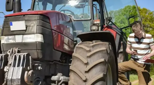 Zwei Männer besprechen den Einsatz eines Traktors. Der jüngere schaut aufs Handy, der ältere hält eine Mappe. Ein guter Verdienst als Fachkraft Agrarservice ist wichtig.
