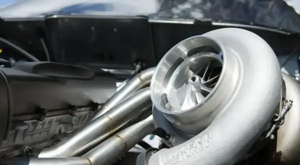 Błyszcząca turbosprężarka w silniku p0299 vw. Metalowe kolektory wydechowe i błyszcząca obudowa silnika.