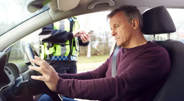 Mann am Steuer, Polizist mit Handy. Die Konsequenzen von Alkohol am Steuer sind eine empfindliche Strafe.