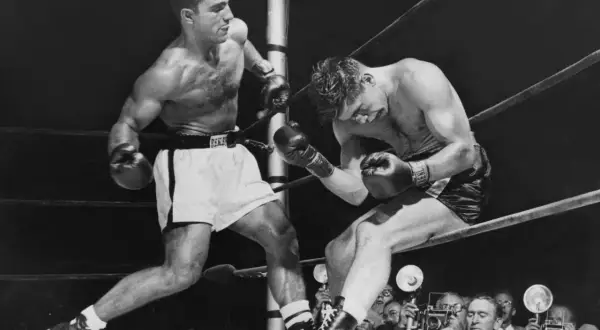 Two boxers in a ring, one on the offensive. Rocky Marciano, who won all 49 of his professional fights, is depicted here.
