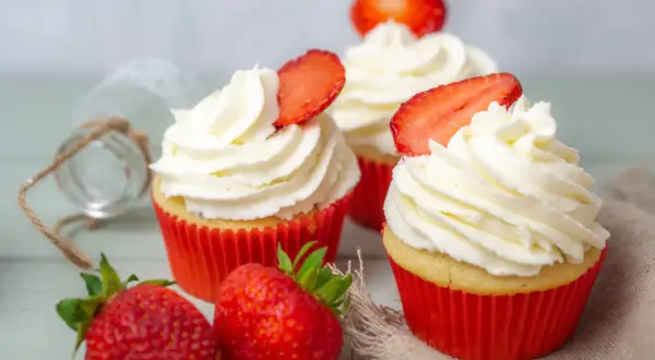 Erdbeer Cupcakes mit weißer Creme und frischen Erdbeeren, dekoriert mit Erdbeerscheiben.