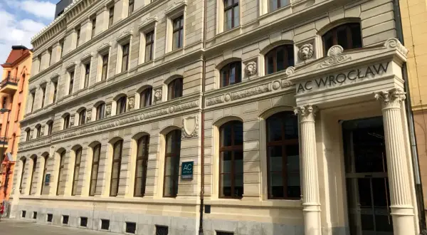 Elegancki budynek AC Hotel Wrocław z kamienną fasadą i ozdobnymi detalami.