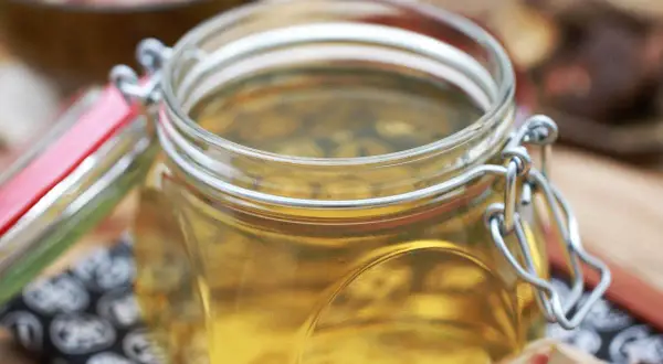 Goldgelbe Flüssigkeit in einem Bügelglas, die anzeigt, was ist Dashi.
