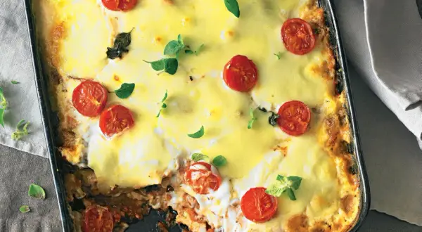 Herzhafte low carb Lasagne mit geschmolzenem Käse und Kirschtomaten, garniert mit frischen Kräutern.