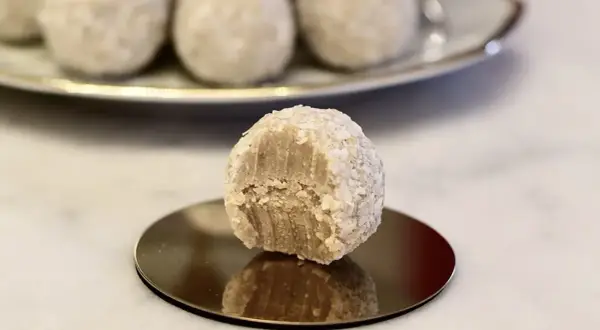 En bit tagen ur en av de fluffiga vita chokladbollarna, som är rullade i kokosflingor.