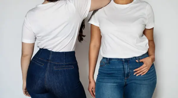 Dwie kobiety w białych T-shirtach i dżinsach. Jedna z nich ma podkreślone szerokie biodra.