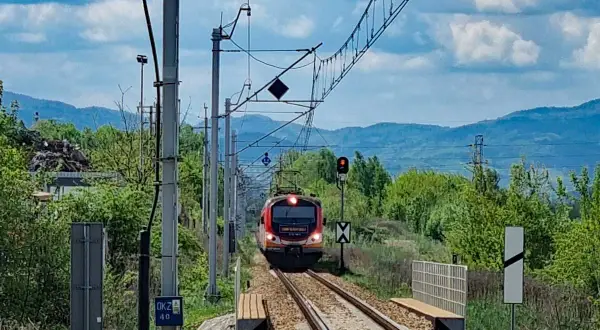 Pociąg zbliża się do stacji, a krajobraz zapowiada podróż, jak dojechać pociągiem do Krynicy-Zdroju.