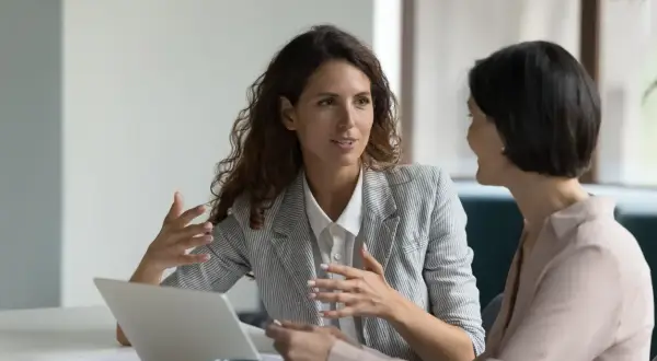 Due donne discutono di un mutuo senza ipoteca, con un laptop aperto sul tavolo.