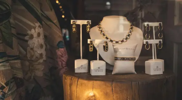 Elegancka biżuteria, w tym naszyjnik, bransoletka i kolczyki, prezentowana na drewnianym pniu. Złom złota w połączeniu z czernią tworzy luksusowy efekt.