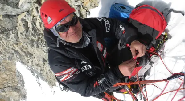 Alpinista w kasku i okularach, który nie ma lęku wysokości, przygotowuje sprzęt na dachu świata.