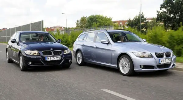 Dwa BMW E90 2.0 benzyna jadące obok siebie. Jeden to ciemny sedan, drugi to jasny kombi.