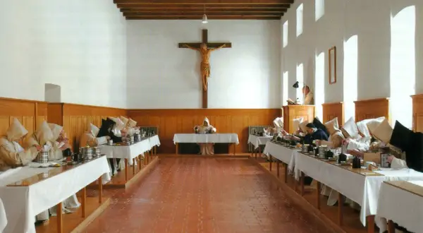Mönche in der Kartause Marienau speisen schweigend an langen Tafeln unter einem Kruzifix.