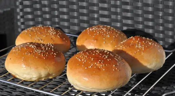 Fünf goldbraune Burgerbrötchen mit Sesam, frisch gebacken nach einem tollen burger buns rezept.
