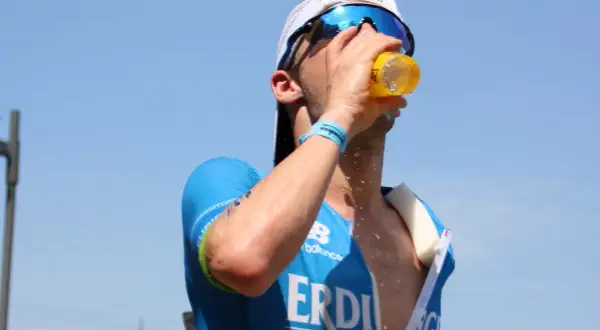 Triathlet trinkt bei heißem Wetter. Sport bei Hitze erfordert Flüssigkeitszufuhr.