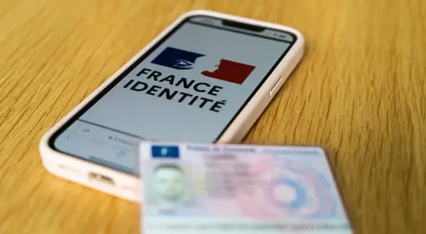 Un smartphone affiche "France Identité", à côté d'une carte d'identité physique. Le futur permis sur téléphone est en préparation.