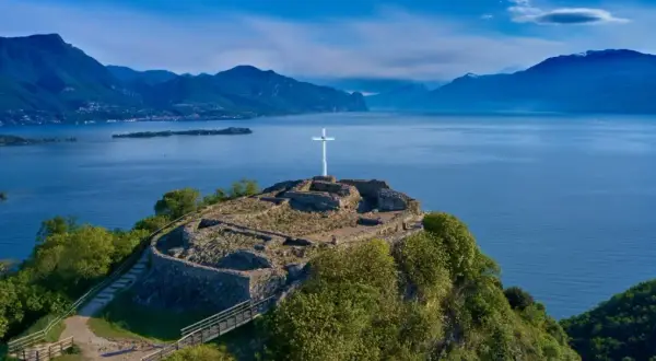 Rovine di un castello con una croce bianca su una collina a Manerba del Garda. Vista panoramica sul Lago di Garda e le montagne.