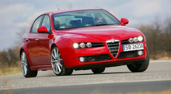 Czerwona Alfa Romeo 159 z włączonymi światłami, widoczne żarówki alfa 159.