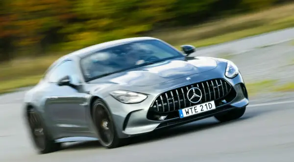Grå Mercedes AMG GT accelererar på en väg. Lär dig hur startar man en manuell bil och njut av körglädjen.