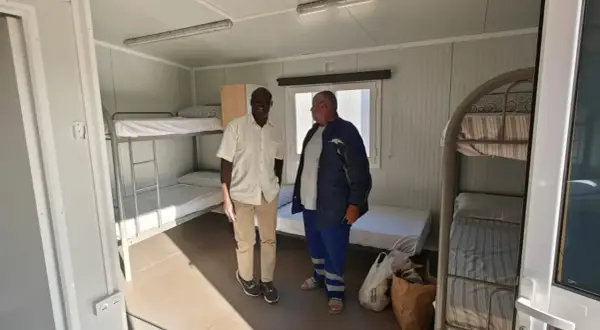 Dos hombres observan literas en un alojamiento temporal, un ejemplo de trabajo a cambio de alojamiento.