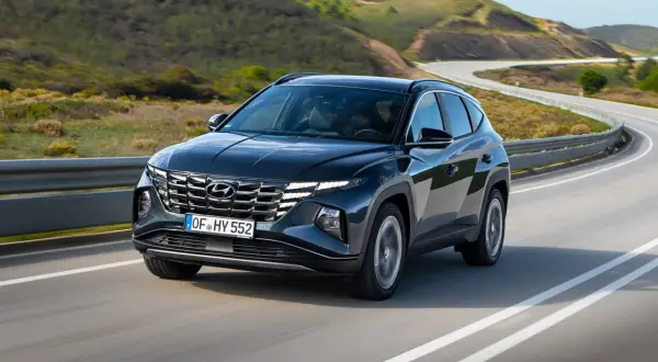 Ciemnoszary Hyundai Tucson na zakręcie drogi. Sprawdź jego imponujące hyundai tucson wymiary i ciesz się jazdą po malowniczej trasie.