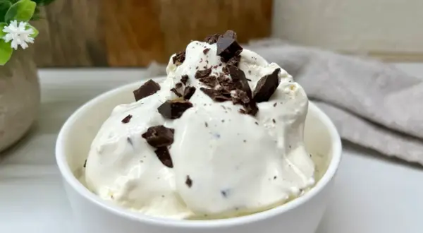 Lody stracciatella w białej miseczce, posypane kawałkami czekolady.