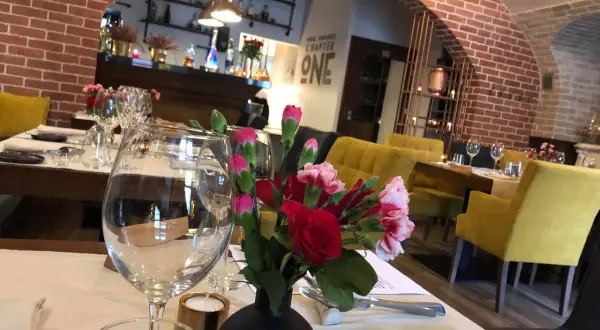 Stolik w jednej z klimatycznych restauracji Lublin. Kwiaty, kieliszki i żółte fotele tworzą przytulną atmosferę.