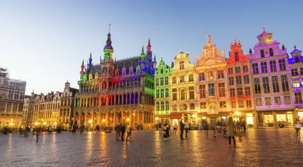 Kolorowe budynki na Grand Place w Brukseli, idealne na święta w Belgii. Ludzie spacerują po brukowanym placu o zmierzchu.