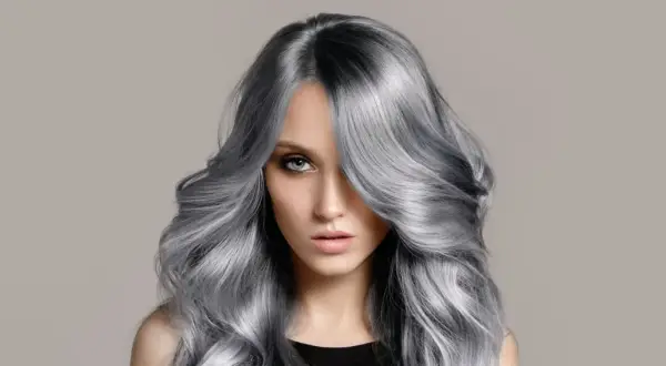 Frau mit voluminösem, welligem Haar in einem modernen balayage grau Farbton.