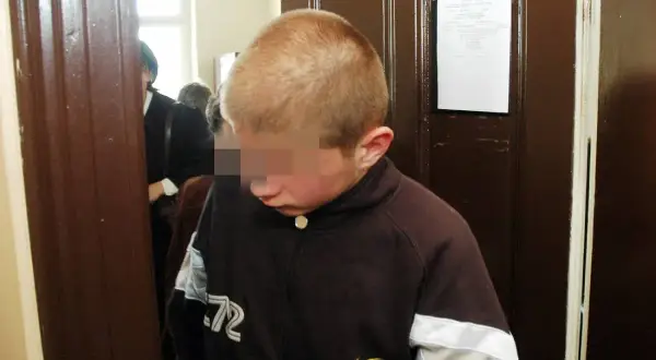 Chłopiec w brązowej bluzie, który jest nieletni, ale w kontekście prawnym może być traktowany jako małoletni.