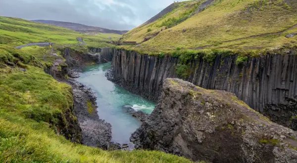Un río turquesa serpentea entre cañones de basalto en Islandia, evocando la majestuosidad de los fiordos islandeses.