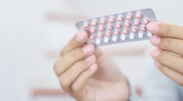 Dłoń trzyma blister z tabletkami antykoncepcyjnymi. Wiele osób szuka informacji o tabletki antykoncepcyjne nazwy.