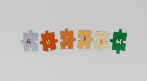 Kolorowe puzzle układają się w napis AUTISM, symbolizując złożoność i różnorodność stopni autyzmu u dzieci.