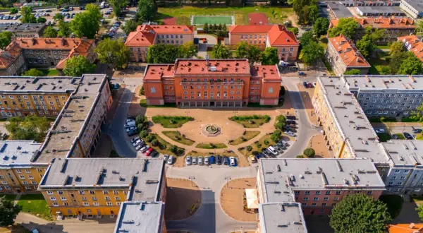 Osiedle Otylia w Tychach z lotu ptaka. Centralny budynek z pomarańczową fasadą, plac z fontanną i otaczające go bloki mieszkalne.