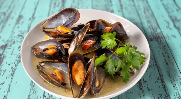 Un plat de moules au roquefort, garni de persil frais, baignant dans une sauce crémeuse. Un délice à savourer.