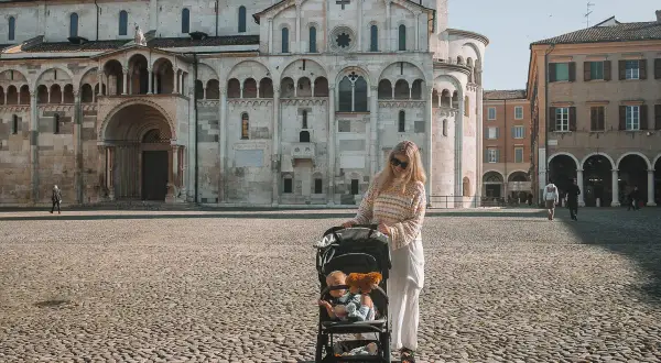 Kobieta z wózkiem dziecięcym na placu przed katedrą w Modenie. To piękne miejsce, które warto zobaczyć, zwłaszcza z taką rodzinną wycieczką.